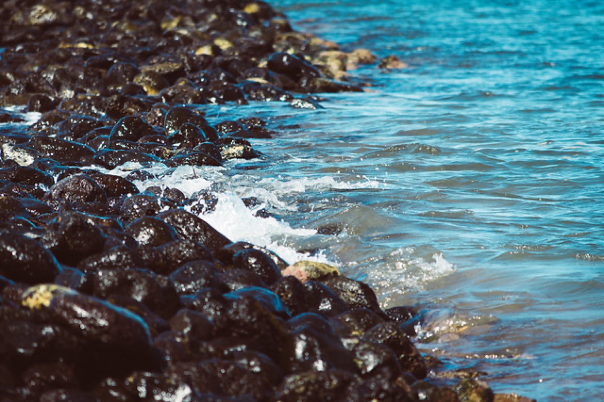 Waves washing over dark volcanic rocks along a Maui shoreline